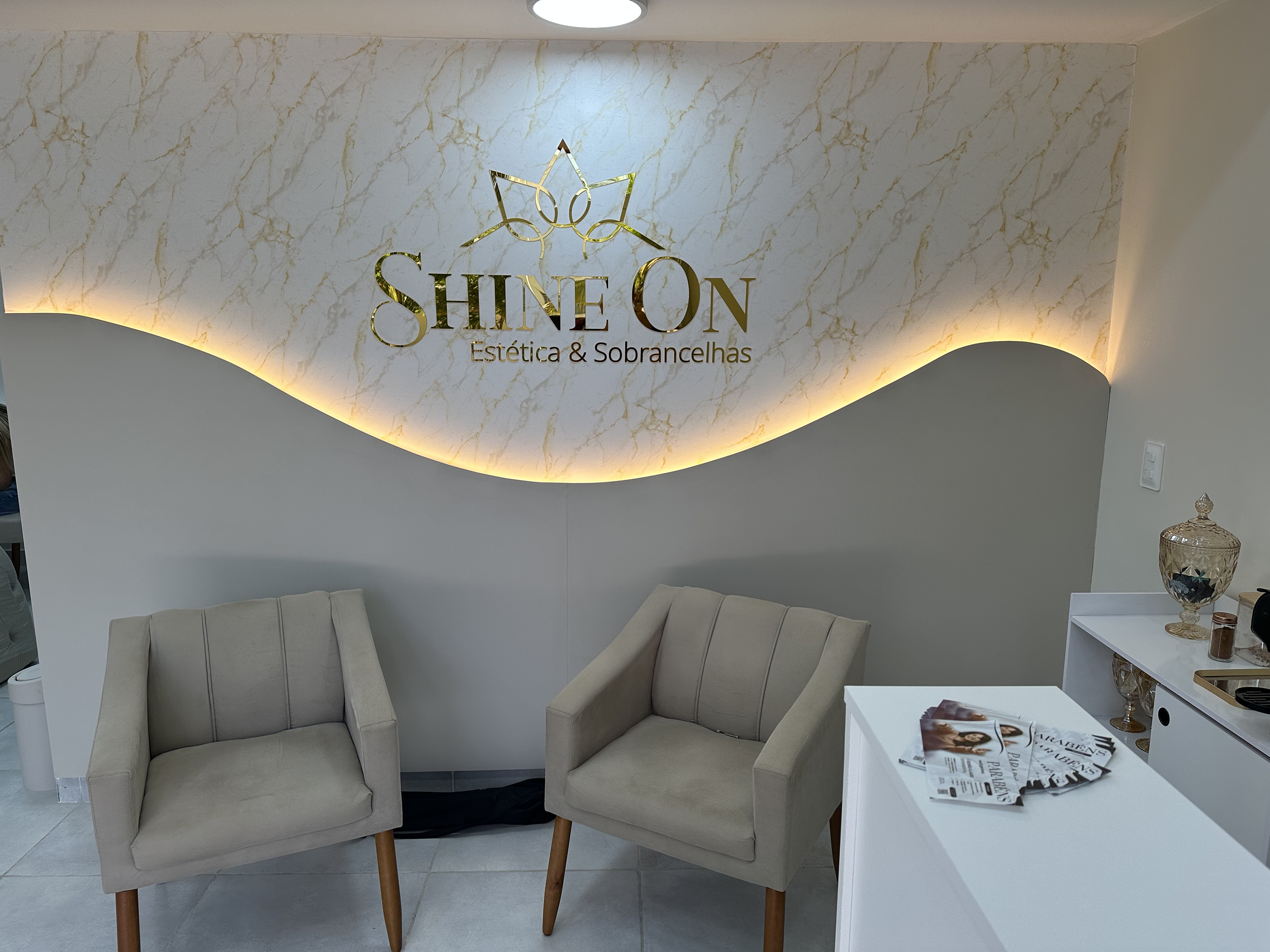 Recepção do Stúdio Shine com poltronas claras e iluminação indireta